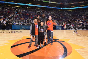 Three students with teacher and basketball player on center court